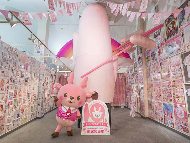 画像:「世界一大きな岩下の新生姜ヘッド」の横でポーズを決めるイワシカちゃん